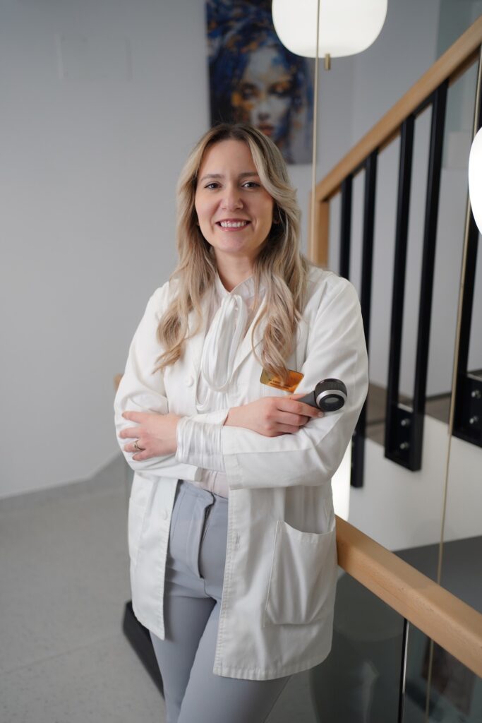 Portret al dr. Cătălina Voinea, medic specialist dermatovenerologie, cu dermatoscopul în mână.